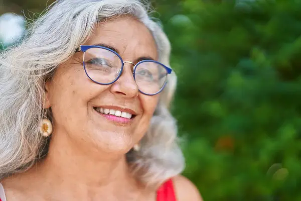 Middle age grey-haired woman smiling confident standing at park