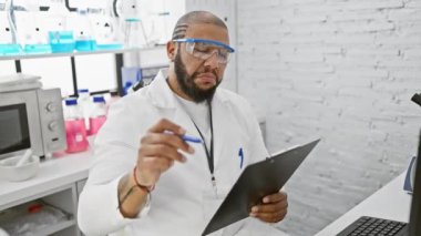 Kendine güvenen siyah bilim adamı modern bir laboratuvar ortamında verileri bir pano ile analiz ediyor..