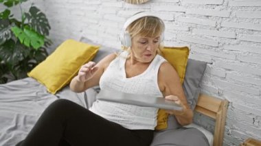 Tükenmiş orta yaşlı sarışın kadın laptopunu rahatça bitiriyor rahat bir yatak odasında, dinlendirici bir uykuya dalmaya hazır.