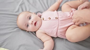 Sevgi dolu bir anne, sıradan giyinmiş, küçük kızını evde güzel kıyafetlerle giydirirken, evdeki oturma odasındaki kanepede oturup, aile ilişkilerinin güzel bağlarını ifade ederken,.