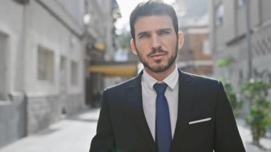 Yakışıklı İspanyol takım elbiseli genç adam şehir sokaklarında güven içinde poz veriyor, profesyonellik ve stil tasvir ediyor..
