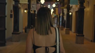 Dubai 'de geleneksel Arap çarşısını keşfeden gülümseyen genç kadın, koridoru aydınlatan fenerler..