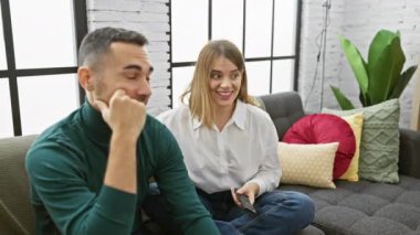 Bir kadın ve bir erkek, sıcak, modern bir oturma odasında keyifli bir anı paylaşıyorlar..