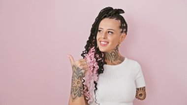 Neşeli İspanyol ampüte kadın uzun boylu, parlak gülümseyen ve başparmak yukarı bakan, Pembe izole arka plan üzerinde fotokopi alanı işaret