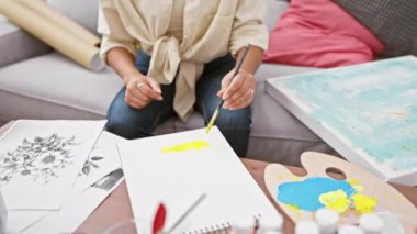 Neşeli genç İspanyol ressam, stüdyoda koltukta oturmuş, mutlu bir ifadeyle parmaklarının arasından bakıp, eliyle 