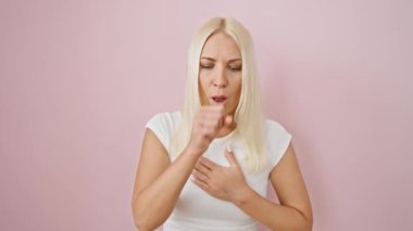 Soğuk algınlığı veya bronşit belirtileri gösteren genç ve kötü bir sarışın, pembe bir arka planda tek başına duruyor, sağlık hizmetleri uyarılarını artırıyor.