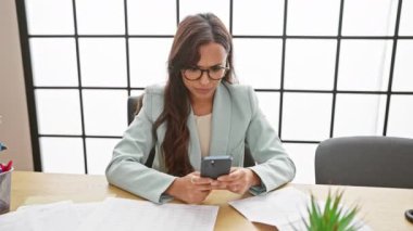 Üzgün ve stresli İspanyol kadın işçi, genç ve güzel, ofiste yoğun iş telefonu işleriyle boğuşuyor.