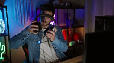 Kulaklık takan genç bir İspanyol gece renkli ışıklandırmalı bir odada oyun oynuyor..