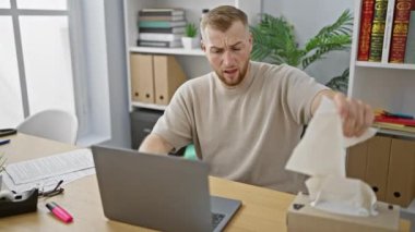 Genç bir adam ofis masasında çalışırken hapşırır ve mendil kullanır. İş ortamında hastalık tasvir eder..