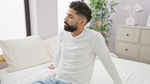 一个体贴入微 留着胡子的年轻人坐在一间现代化的卧室里 在家里表现出沉思和放松 — 图库视频影像