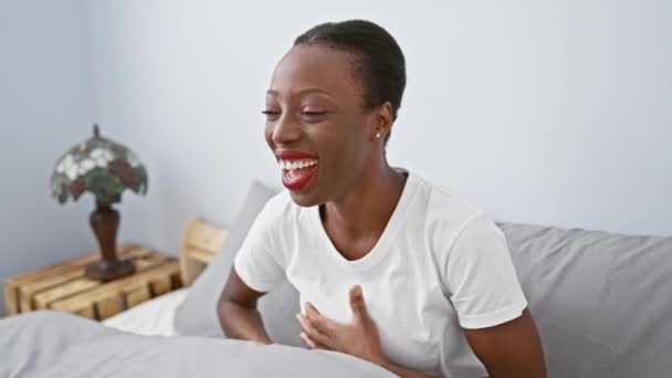 ジョイフルなアフリカ系アメリカ人女性は 寝室のベッドに横たわって大声で笑う 彼女の手 彼女はすべての笑顔 楽しいと陽気でいっぱいです — ストック動画
