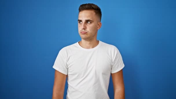 一个穿着白衬衫的年轻人在孤零零的蓝色背景下摆出各种表情 — 图库视频影像