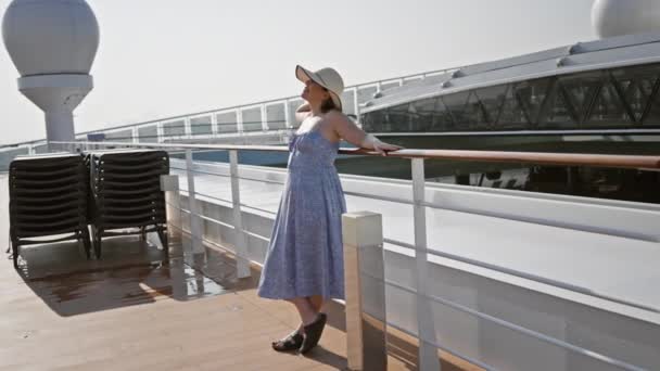 一位穿着夏装戴帽子的悠闲女人在阳光灿烂的游轮甲板上享受着闲暇时光 — 图库视频影像