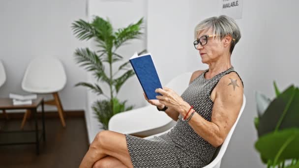 Elegante Seniorin Liest Ein Buch Einem Modernen Weißen Warteraum Mit — Stockvideo