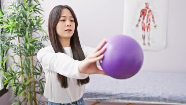 中国妇女在诊所拿着紫色球进行康复锻炼 描绘医疗保健和理疗 — 图库视频影像