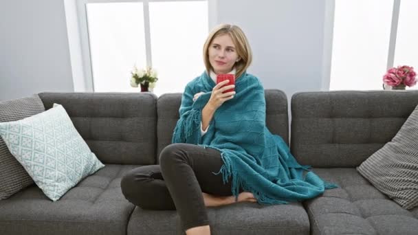 Entspannte Blonde Frau Genießt Eine Tasse Kaffee Auf Einem Bequemen — Stockvideo