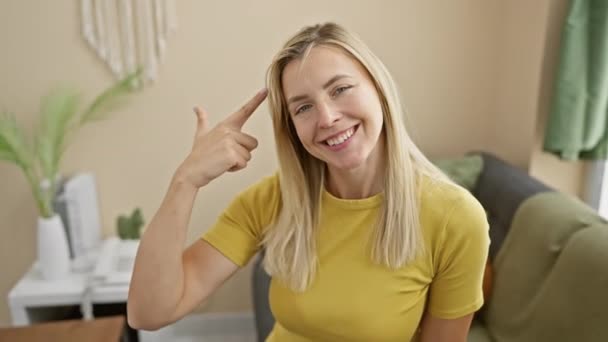Mulher Loira Jovem Alegre Uma Camiseta Brincando Apontando Para Cabeça — Vídeo de Stock