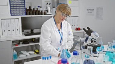 Çalışkan, orta yaşlı, bilim laboratuarında önemli notlar alırken sırt ağrısıyla savaşan sarışın bir kadın.