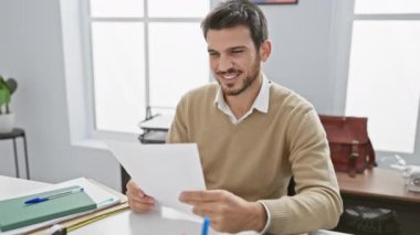 Ofiste, belgelere bakan, işyerindeki başarıyı ve profesyonelliği resmeden neşeli, genç bir İspanyol..