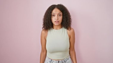 Vay canına! Genç, şaşırtıcı derecede güzel İspanyol bir kadın, kıvırcık saçlı, şaşkın bir yüz ifadesi, yüzünü aydınlatan, pembe izole edilmiş arka planda neşeli bir şekilde duran, elleri şaşkın bir sevinçle hareketli..