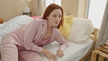 Huzurlu, genç, kızıl saçlı bir kadın renkli yastıklarla dolu rahat bir yatak odasında dinleniyor. Huzurlu bir atmosfer yayıyor..