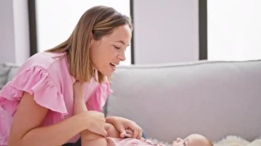 Neşeli anne kanepede uzanıyor, evde mutlu kızı öpüyor, güzel bir yaşam tarzı paylaşıyor.