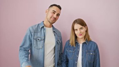 Güzel bir çift, el sallayıp selamlaşıyorlar! Kot gömleklerle bir aradayız, pembe ve izole bir arkaplanda kendinden emin bir şekilde selamlaşıyoruz..