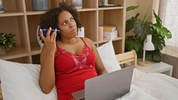 拥有辫子的非裔美国妇女在卧室里使用笔记本电脑和电话 — 图库视频影像
