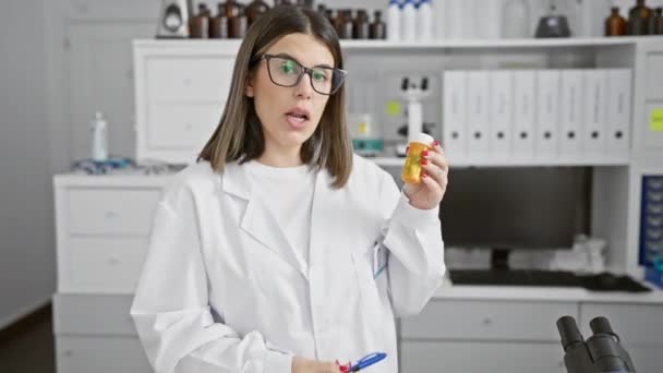 一个带着眼镜在实验室里拿药的惊慌失措的女人 带着好奇的表情 — 图库视频影像