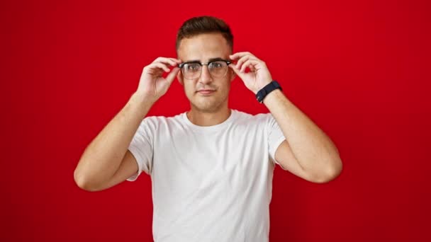 Handsome Young Adult Hispanic Man Smiling Adjusting Glasses Isolated Red — Stock Video