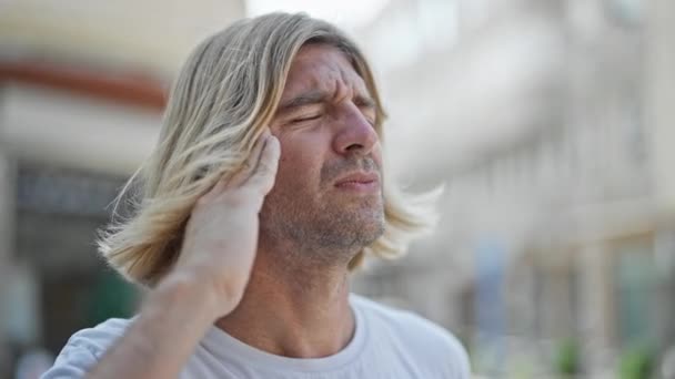 Bolestivý Muž Dlouhými Blond Vlasy Zažívá Bolest Hlavy Venku Městě — Stock video
