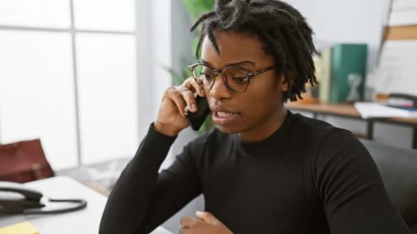 オフィスで強調された電話で話すメガネのドレッドロックを持つアフリカ系アメリカ人女性 — ストック動画