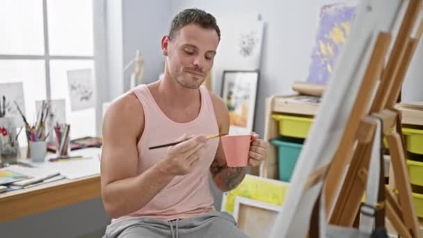 微笑的男人拿着咖啡杯在明亮的画室里作画 — 图库视频影像