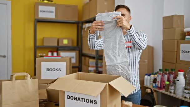 Young Hispanic Man Volunteering Donation Center Organizing Clothing Various Goods — Stock Video