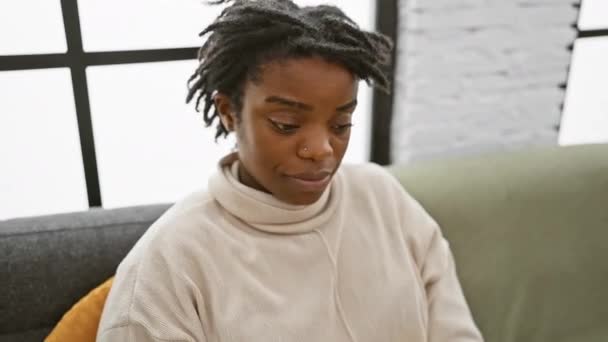 Surpresa Olhos Abertos Jovem Negra Com Dreadlocks Confiantemente Sentada Casa — Vídeo de Stock