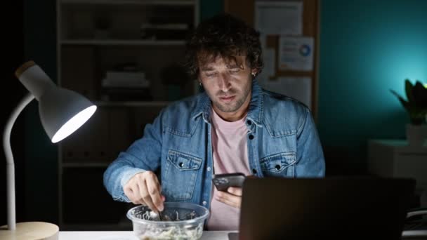 Przemyślany Człowiek Wielozadaniowy Biurze Nocy Jedzący Podczas Korzystania Smartfona Laptopa — Wideo stockowe