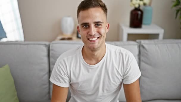 Yakışıklı Genç Adam Gülümsüyor Bir Kanepede Otururken Başparmağını Kaldırıyor — Stok video
