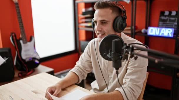 Young Man Wearing Headphones Speaks Microphone Bright Red Recording Studio — Stock Video