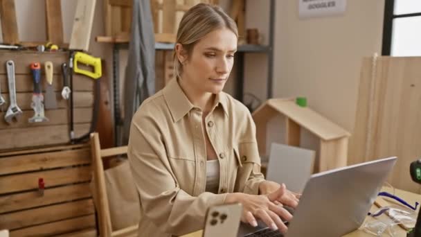Young Determined Blonde Woman Confidently Navigates Laptop Carpentry Workshop Displaying — Stock Video