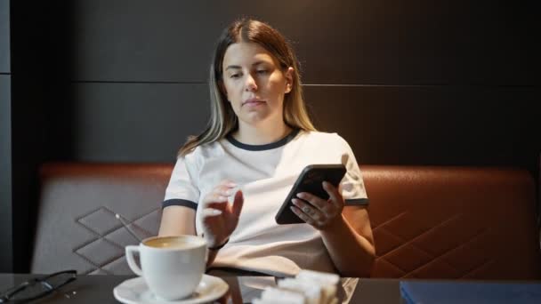 Νεαρή Ενήλικη Ισπανόφωνη Γυναίκα Που Χρησιμοποιεί Smartphone Και Πίνει Καφέ — Αρχείο Βίντεο