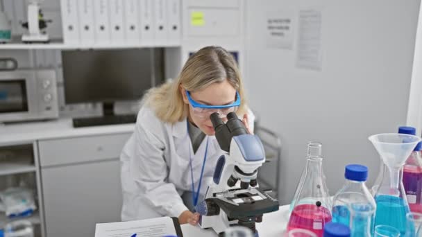 現代の実験室で顕微鏡を用いた実験室コートの女性科学者 — ストック動画