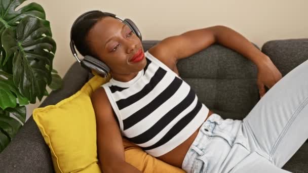 Mujer Afroamericana Confiada Disfrutando Felizmente Música Acostada Sofá Del Hogar — Vídeo de stock