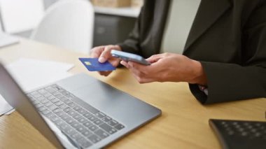 Patroniçe daktilo ediyor ve internetten çalışıyor. Akıllı telefonu kullanarak ofis masasındaki kredi kartıyla işlem yapıyor.