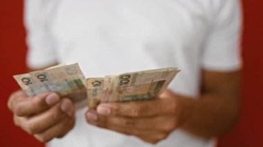 Finansal kavramları tasvir eden, kırmızı bir arka plan karşısında, bir adamın ellerinin Polonya parasıyla yakın plan fotoğrafı..