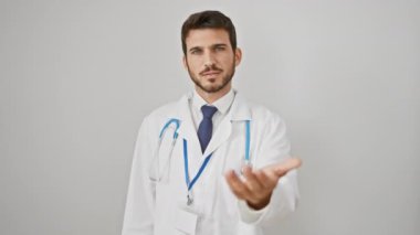 Yakışıklı, sakallı ve steteskop takan gülümseyen İspanyol genç adam, beyaz izole bir geçmişe karşı dostane bir el hareketi sunuyor, kabulü simgeliyor ve yardım etmeye hazır.