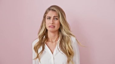 Pembe elbiseli genç, korkusuz sarışın kadın tiksinti duyuyordu. İzole edilmiş arka planda tek başına duran hoşnutsuz ifadenin hoş bir portresi.