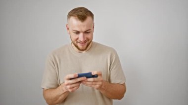 Sakallı genç beyaz bir beyaz arka planda akıllı bir telefonla meşgul olan beyaz bir adam, neşeli ve düşünceli duygular sergiliyor..