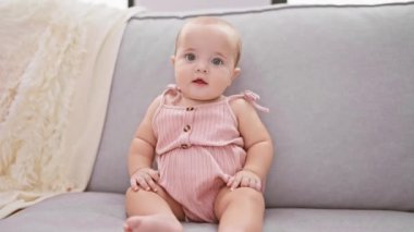 Sevimli yeni doğmuş bebek, evde oturma odasındaki kanepede dinleniyor, küçük sevimli bir gülümseme sergiliyor..