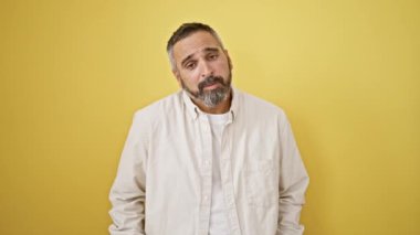 Sarı bir duvara karşı yalvaran gri saçlı, olgun sakallı bir adam. Umut ve endişeyle dolu duygular gösteriyor..