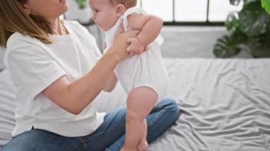 Kendine güvenen anne, eğlenceli anların tadını çıkarıyor, yatakta oturuyor, güzel kızına rahat yatak odasında uykusunun mutluluğunu diliyor. Sıradan, mutlu aile yaşam tarzının mükemmel ifadesi..